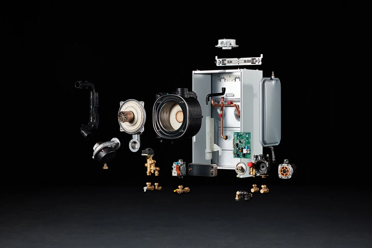 A Baxi combi boiler shown deconstructed, with the heat exchanger, fan, pump, expansion vessel and brass hydraulic fittings laid out around the chassis